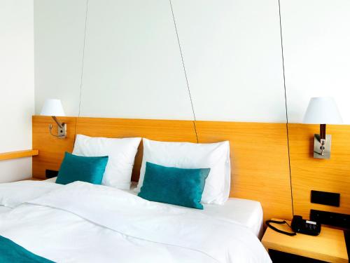 a hotel room with a bed with blue pillows at Regatta Hotel Restauracja Spa in Poznań