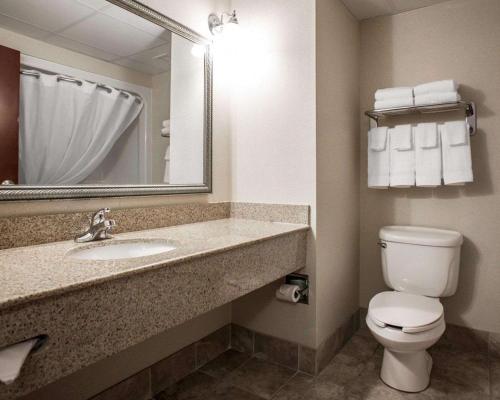 a bathroom with a toilet and a sink and a mirror at Comfort Inn & Suites in Lumberton