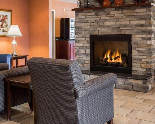 a living room with a fireplace with two chairs and a table at Comfort Inn & Suites Lumberton Central I-95 in Lumberton