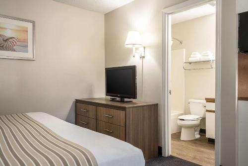 um quarto de hotel com uma cama e uma televisão de ecrã plano em Suburban Studios of Wilmington em Wilmington