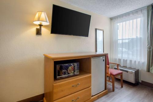 a room with a tv on a wall with a dresser at Rodeway Inn Asheville in Asheville