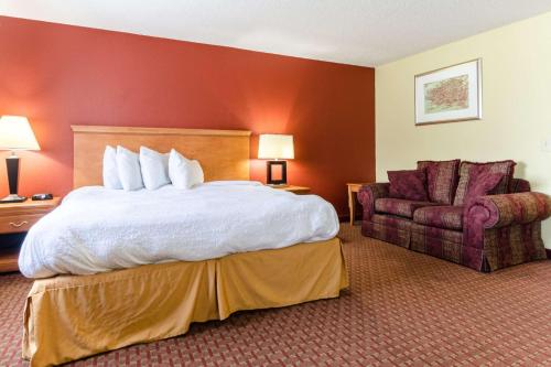 Habitación de hotel con cama y silla en Rodeway Inn & Suites Jacksonville near Camp Lejeune, en Jacksonville