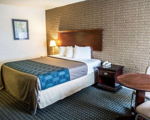 a hotel room with a large bed and a table at Rodeway Inn & Suites Wilmington North in Wilmington