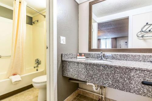 ein Badezimmer mit einem Waschbecken, einem WC und einem Spiegel in der Unterkunft Econo Lodge - Gastonia in Gastonia