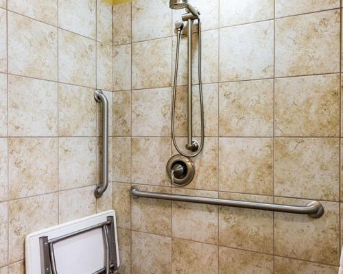 y baño con ducha y pared de azulejos. en MainStay Suites Minot, en Minot