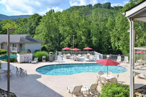 una piscina con sillas, mesas y sombrillas en Quality Inn Cherokee en Cherokee