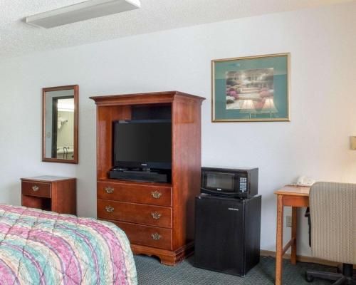 a bedroom with a bed and a dresser with a television at Rodeway Inn in West Fargo