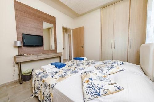 a bedroom with a bed with a tv on the wall at Timotheos Villa in Protaras