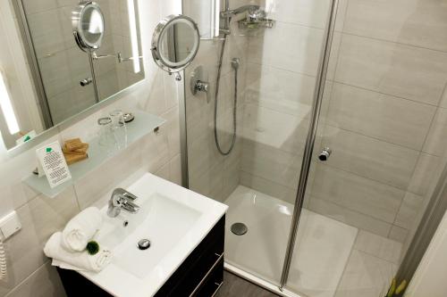 a white bathroom with a shower and a sink at Hotel Wittelsbacher Höh in Würzburg