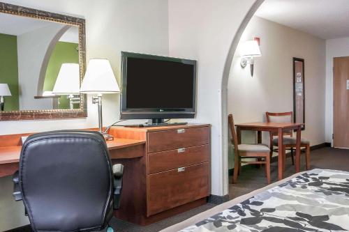 a hotel room with a desk with a television and a chair at Sleep Inn & Suites Conference Center and Water Park in Minot