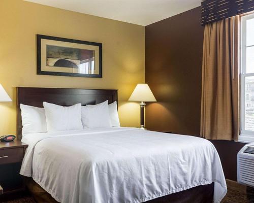 a hotel room with a large bed with white sheets at MainStay Suites Minot in Minot
