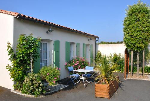 una casa bianca e verde con un tavolo e alcune piante di Hôtel La Galiote en Ré a La Flotte