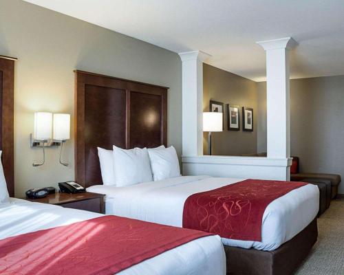 a hotel room with two beds with red sheets at Comfort Suites Medical Center in Fargo