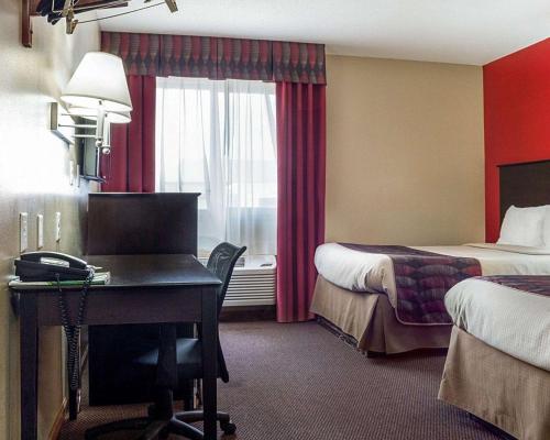a hotel room with a desk and a bedroom with two beds at Econo Lodge Jamestown in Jamestown