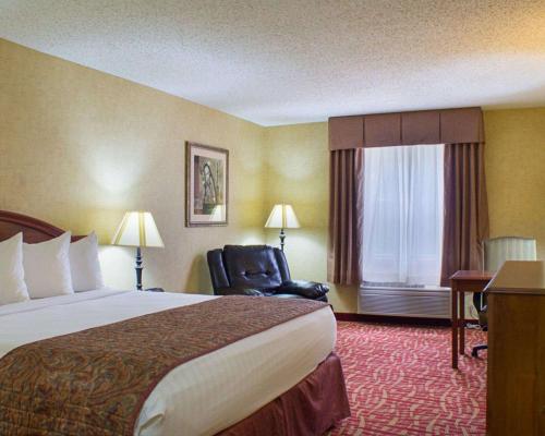 a hotel room with a bed and a chair and a window at Rodeway Inn Columbia Mall Loop in Grand Forks