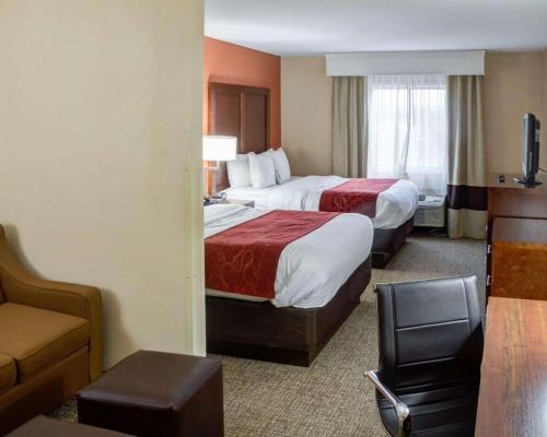 a hotel room with two beds and a chair at Comfort Suites Omaha in Omaha