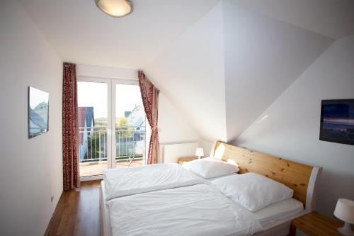 ein Schlafzimmer mit einem weißen Bett und einem Fenster in der Unterkunft Villa Wittow in Wiek auf Rügen 