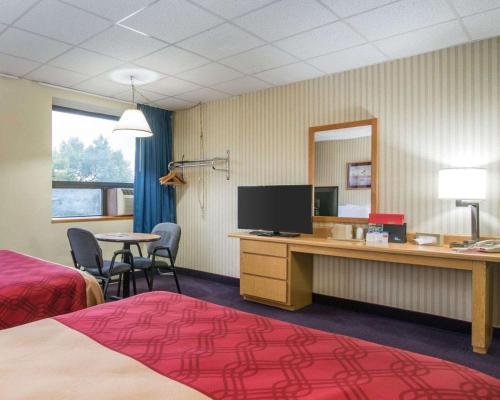 a hotel room with a bed and a desk with a television at Econo Lodge Manchester in Manchester
