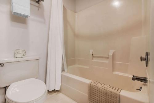 a white bathroom with a toilet and a tub and a shower at Rodeway Inn in Holdrege