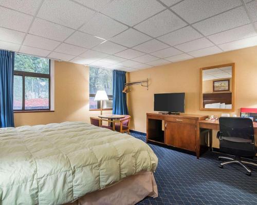 a hotel room with a bed and a desk and a television at Econo Lodge Manchester in Manchester