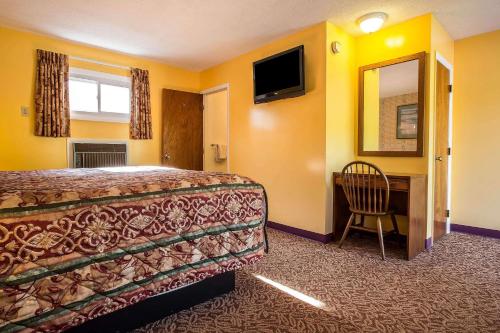 a hotel room with a bed and a desk and a mirror at Rodeway Inn Lincoln I-93 in Lincoln