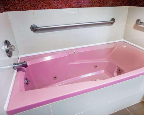 uma banheira rosa sentada na casa de banho em Days Inn by Wyndham Jersey City em Jersey City