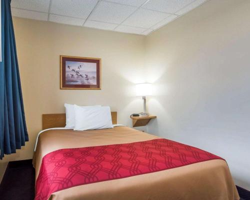 a hotel room with a bed with a red blanket at Econo Lodge Manchester in Manchester
