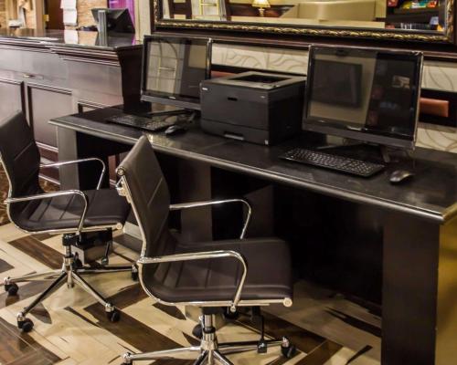 a desk with three monitors and two computers on it at Quality Suites NYC Gateway in North Bergen