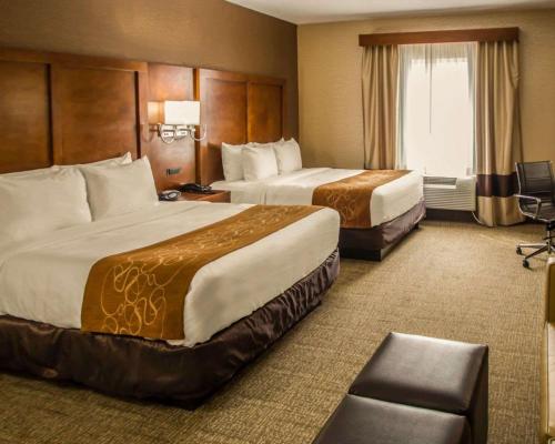 a hotel room with two beds and a chair at Quality Suites NYC Gateway in North Bergen