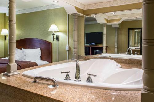 a large bathroom with a tub and a bed at Rodeway Capri Inn in Little Ferry