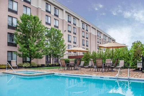 a pool with chairs and umbrellas next to a building at Comfort Inn & Suites Somerset - New Brunswick in Somerset