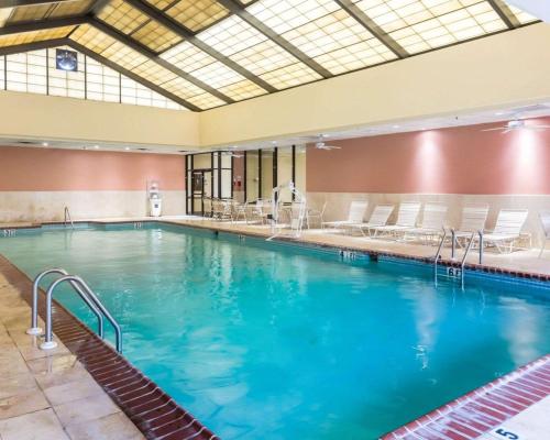 a large swimming pool with blue water and white chairs at Clarion Hotel Somerset - New Brunswick in Somerset