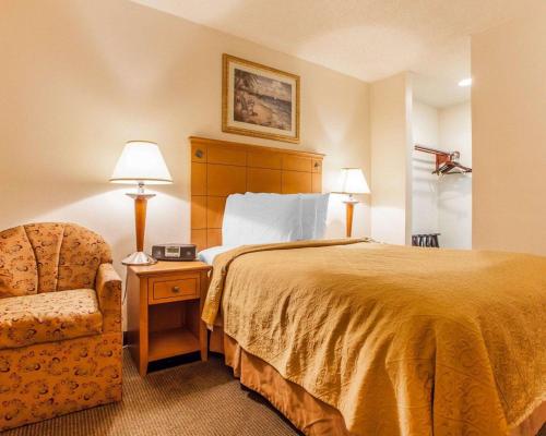 Habitación de hotel con cama y silla en Rodeway Inn Point Pleasant Beach, en Point Pleasant