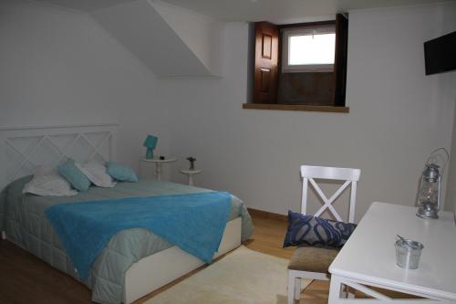 a bedroom with a bed and a chair and a window at Casa da Capela in Paredes de Coura