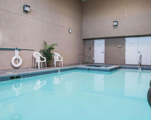 a swimming pool with two chairs and a plant at Econo Lodge Albuquerque Old Town in Albuquerque