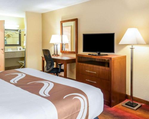 a hotel room with a bed and a desk with a television at Quality Inn & Suites Albuquerque West in Albuquerque