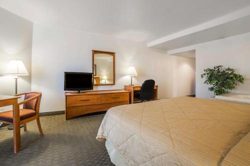 ボルダーシティにあるLake Mead Innのベッド、デスク、テレビが備わるホテルルームです。