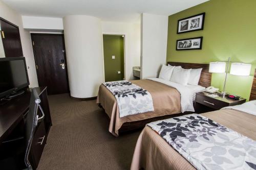 a hotel room with two beds and a flat screen tv at Sleep Inn Gallup in Gallup