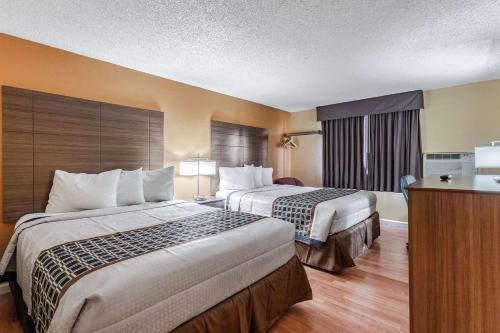 a hotel room with two beds and a television at Rodeway Inn in Farmington