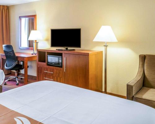 a hotel room with a bed and a tv and a desk at Quality Inn & Suites Albuquerque West in Albuquerque