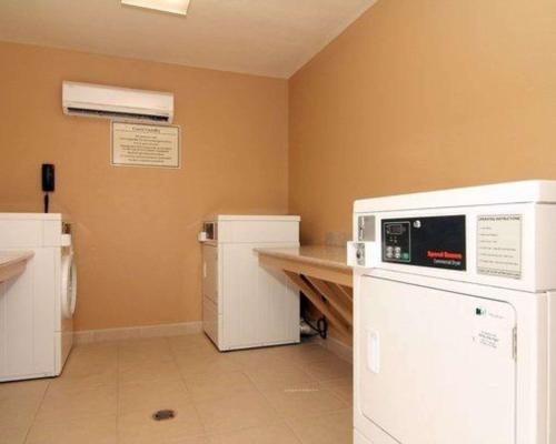 a kitchen with a white refrigerator and a counter at Suburban Studios Alamogordo in Alamogordo