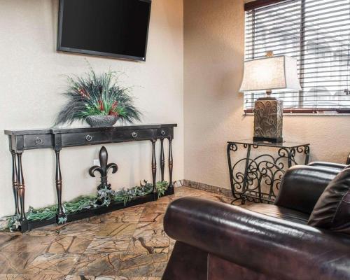 a living room with a couch and a tv on a wall at Suburban Studios Alamogordo in Alamogordo