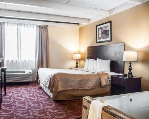 a hotel room with a bed and a bath tub at Quality Inn Buffalo Airport in Cheektowaga