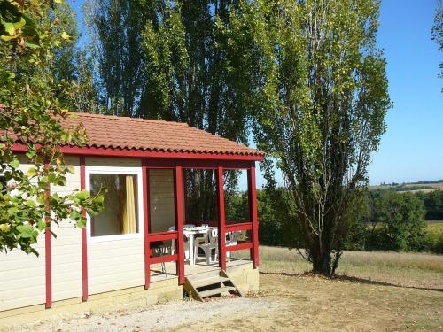 a red and white shed with a table in it at Les Chalets des Mousquetaires in Mirepoix