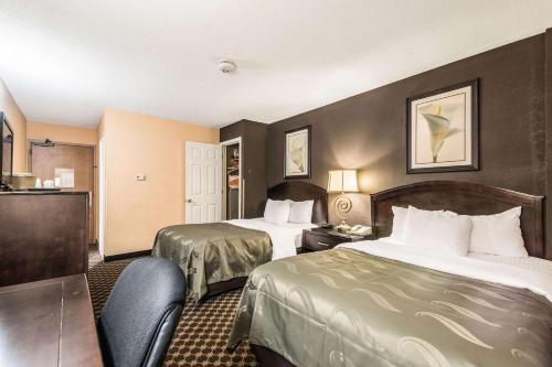 a hotel room with two beds and a desk at Quality Inn Ithaca - University Area in Ithaca