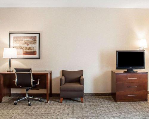 a hotel room with a tv and a chair and a desk at Comfort Inn & Suites Hamburg - Buffalo South in Hamburg