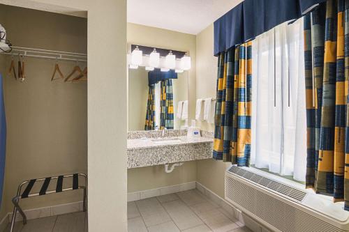 ein Bad mit einem Waschbecken und einem Spiegel in der Unterkunft Rodeway Inn and Suites Ithaca in Ithaca