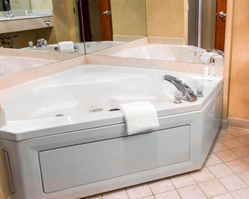 uma banheira branca com um lavatório e um espelho em Comfort Inn & Suites Hawthorne em Hawthorne