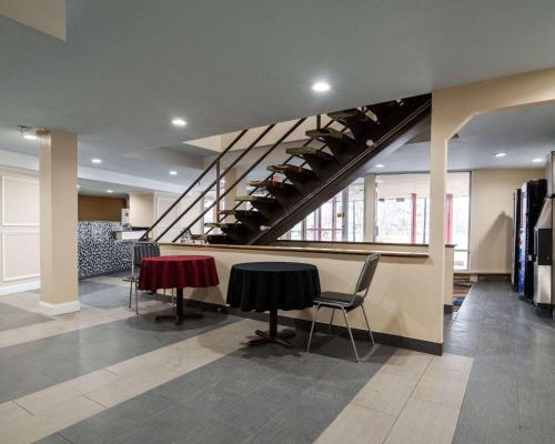 a lobby with a table and chairs and a staircase at Rodeway Inn Syracuse Carrier Circle in East Syracuse
