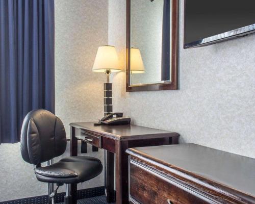 a hotel room with a desk with a lamp and a chair at Paramount Inn in Queens